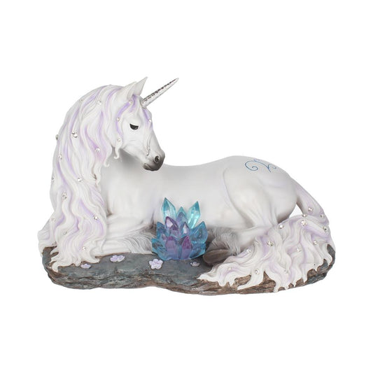 A unicorn reclines on a slab of rock, pink flowers scattered around him.