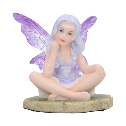 Lavender fairy figurine, seated on a stone path base in a tranquil po
